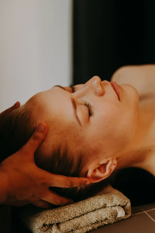 Orientalna pielęgnacja twarzy – masażystka wykonuje masaż głowy i twarzy klientki